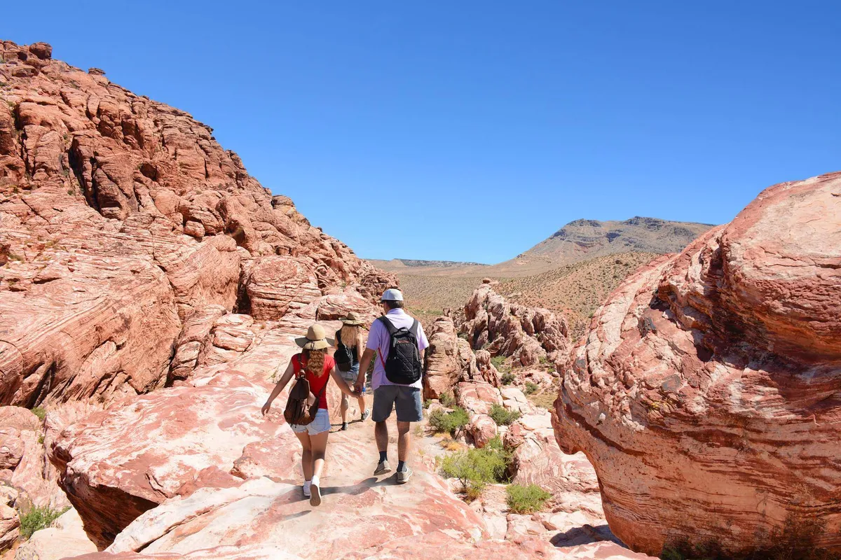 Set against dramatic rock formations and distant mountains, this image captures hikers exploring nature trails. The scene is vibrant and filled with possibilities for outdoor adventure and relaxation in the nearby landscape.