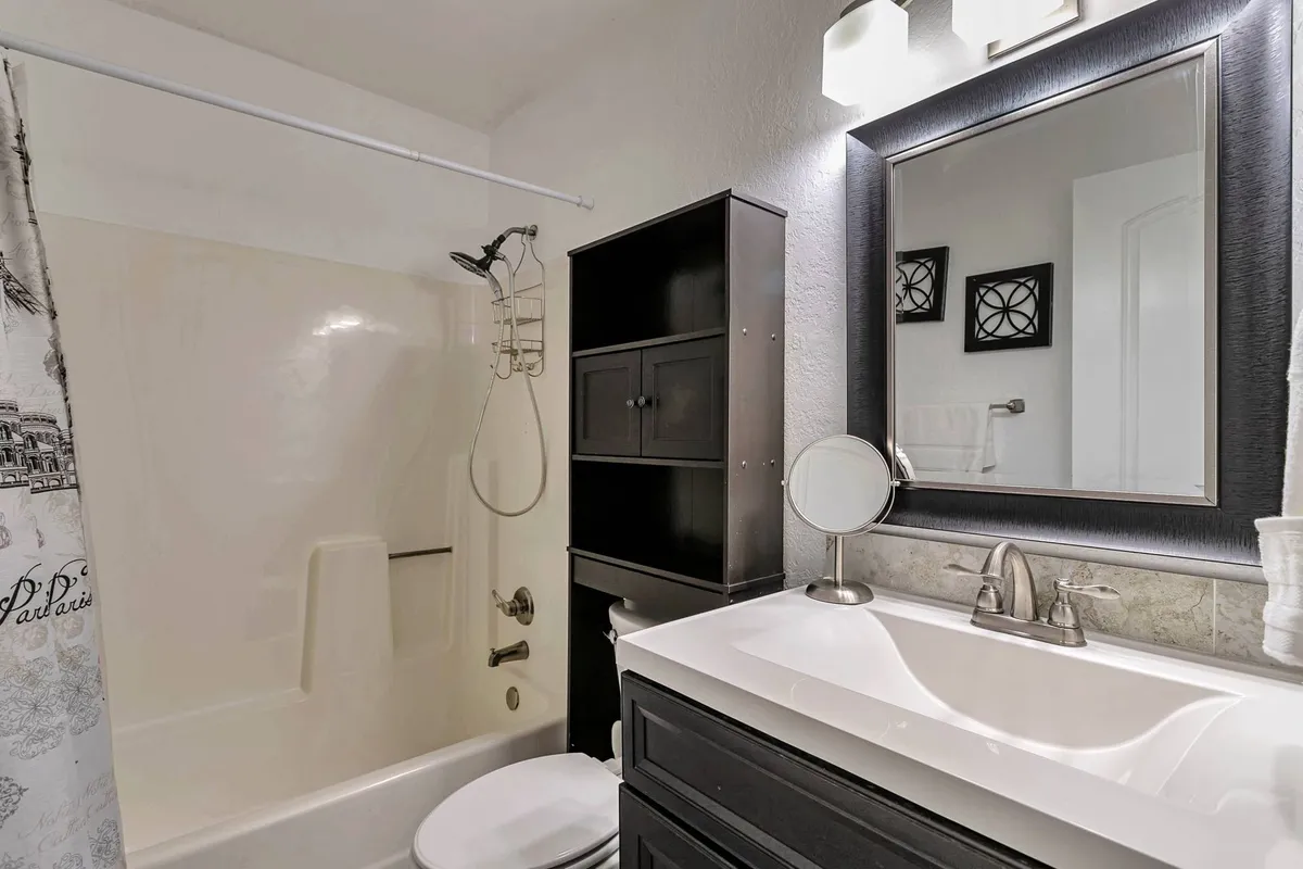 This image features a modern bathroom vanity with a mirrored cabinet and a spacious shower area. The scene is inviting and functional, with plenty of light reflecting off clean surfaces, evoking a sense of hygiene and convenience.